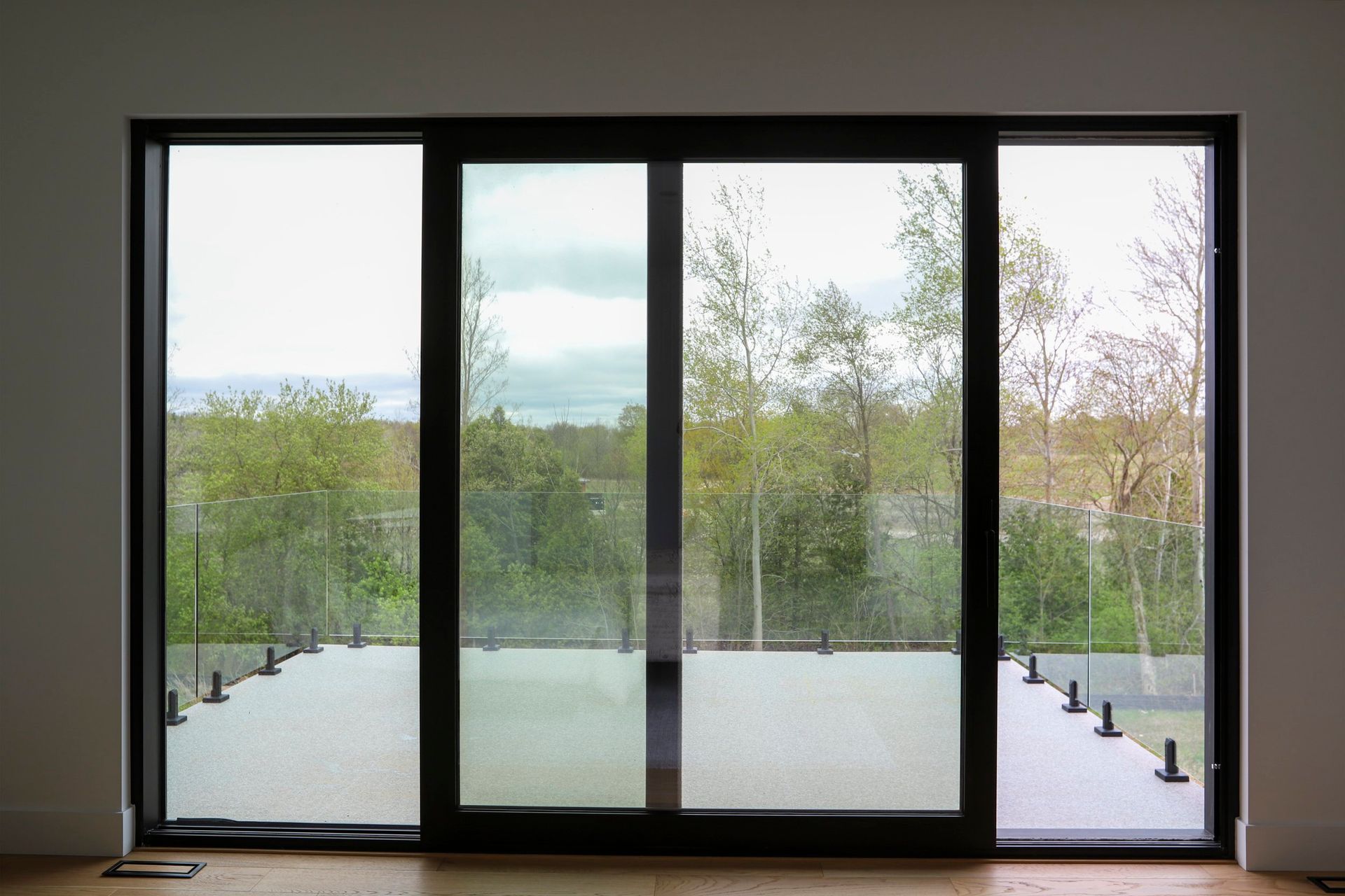 A large sliding glass door with a view of a forest.