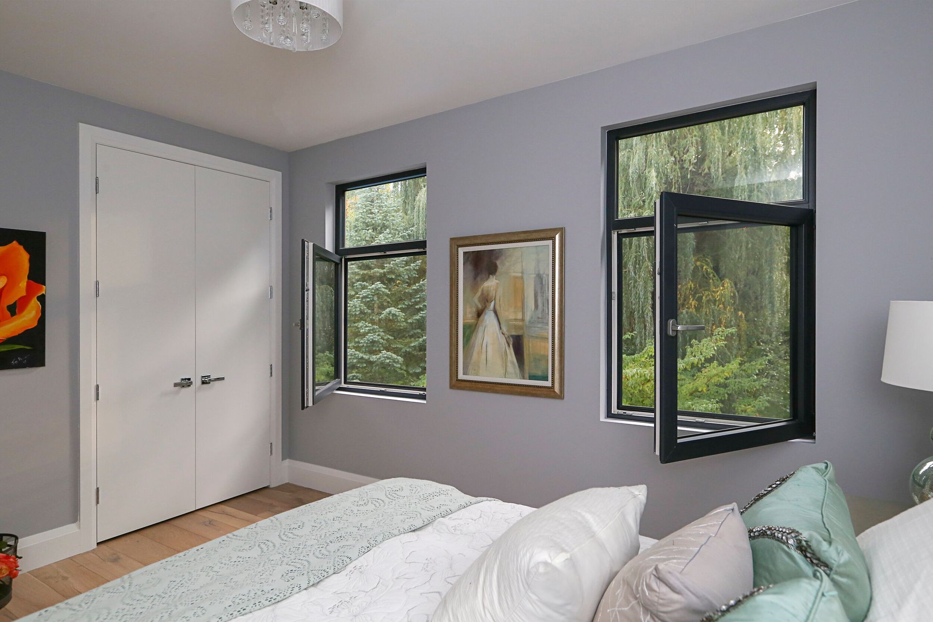 A bedroom with a bed , two windows and a painting on the wall.