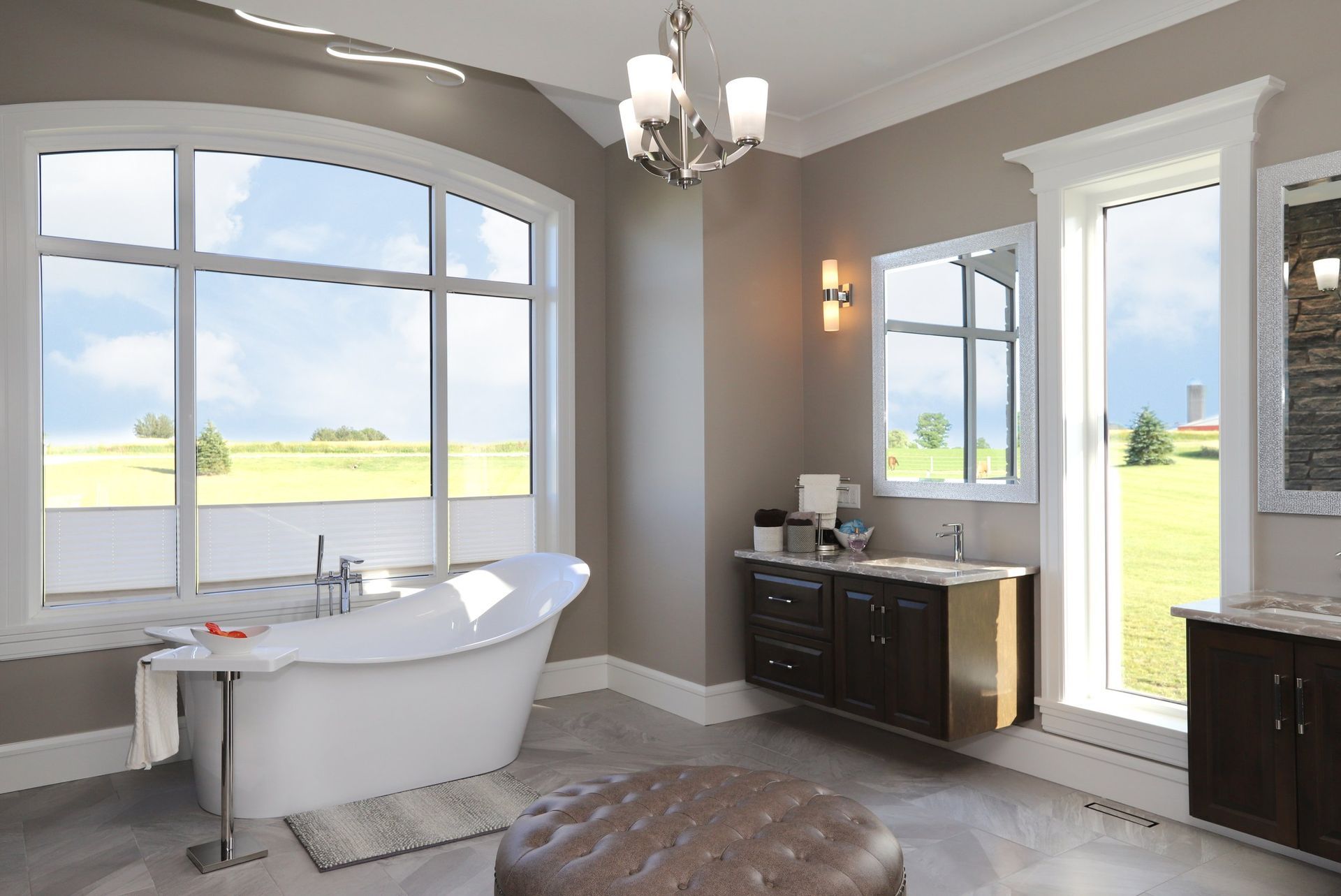 A bathroom with a tub , sink , and large windows.