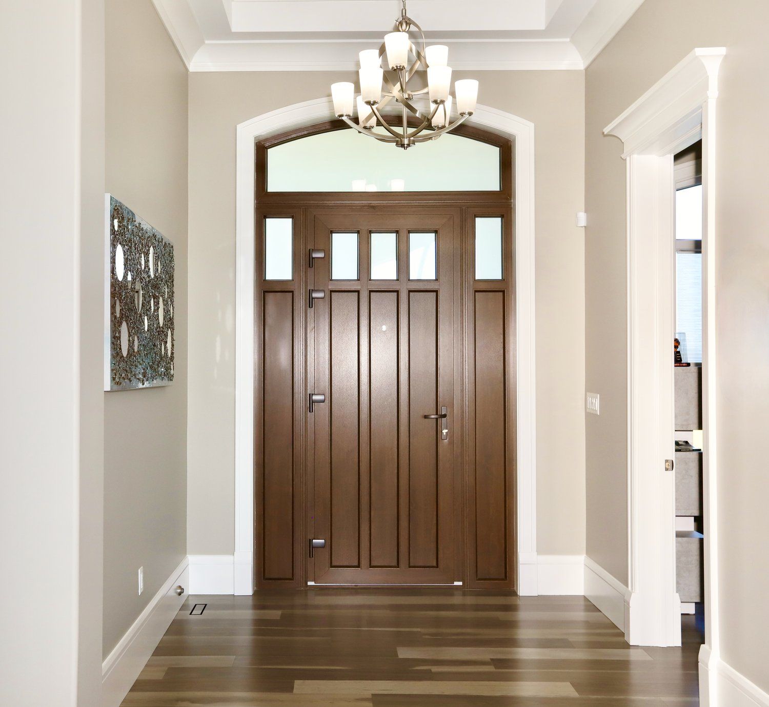 A hallway with a wooden door and a chandelier hanging from the ceiling