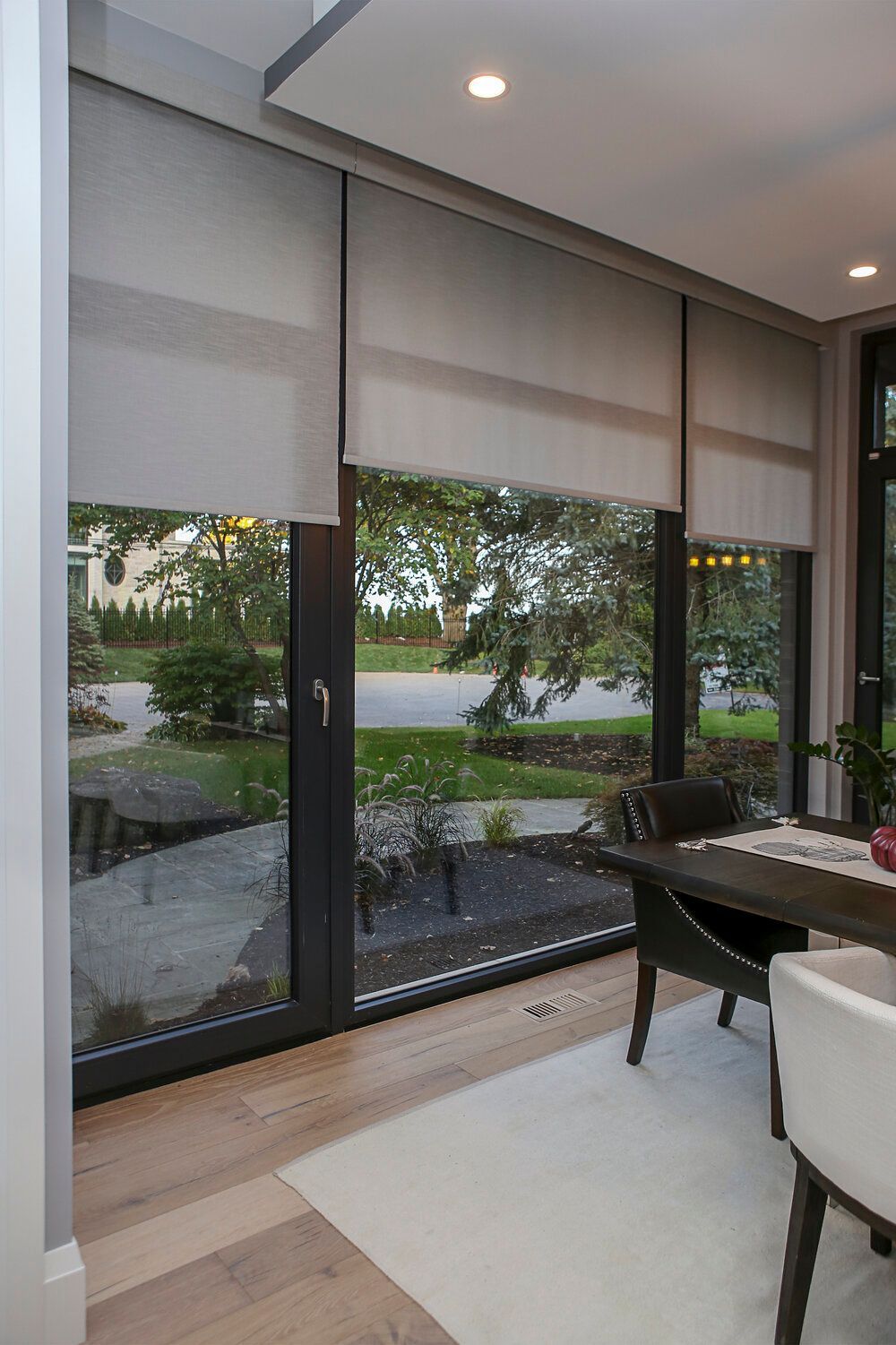 A dining room with a table and chairs and a large window.