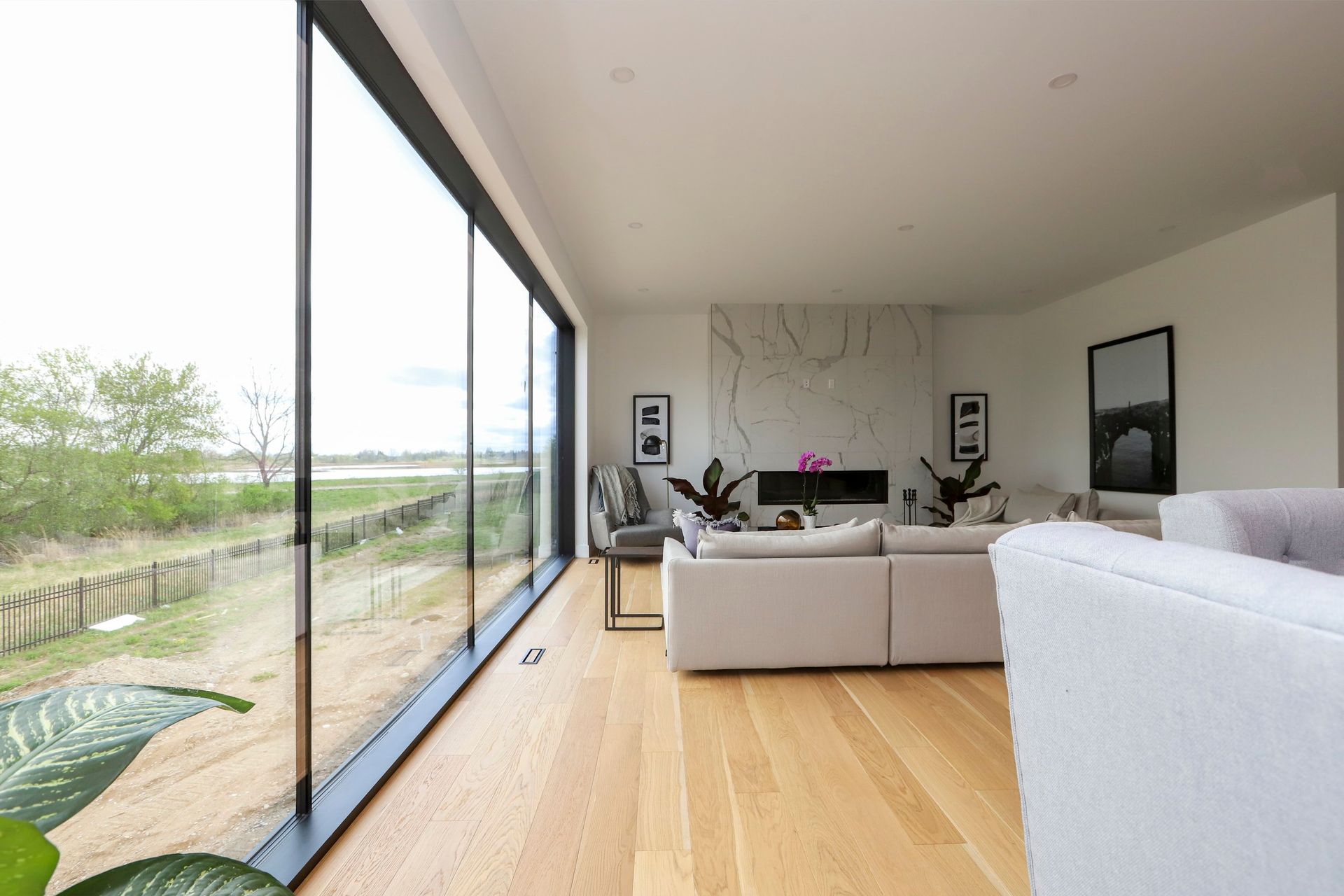 A living room with a couch , chair , fireplace and large windows.