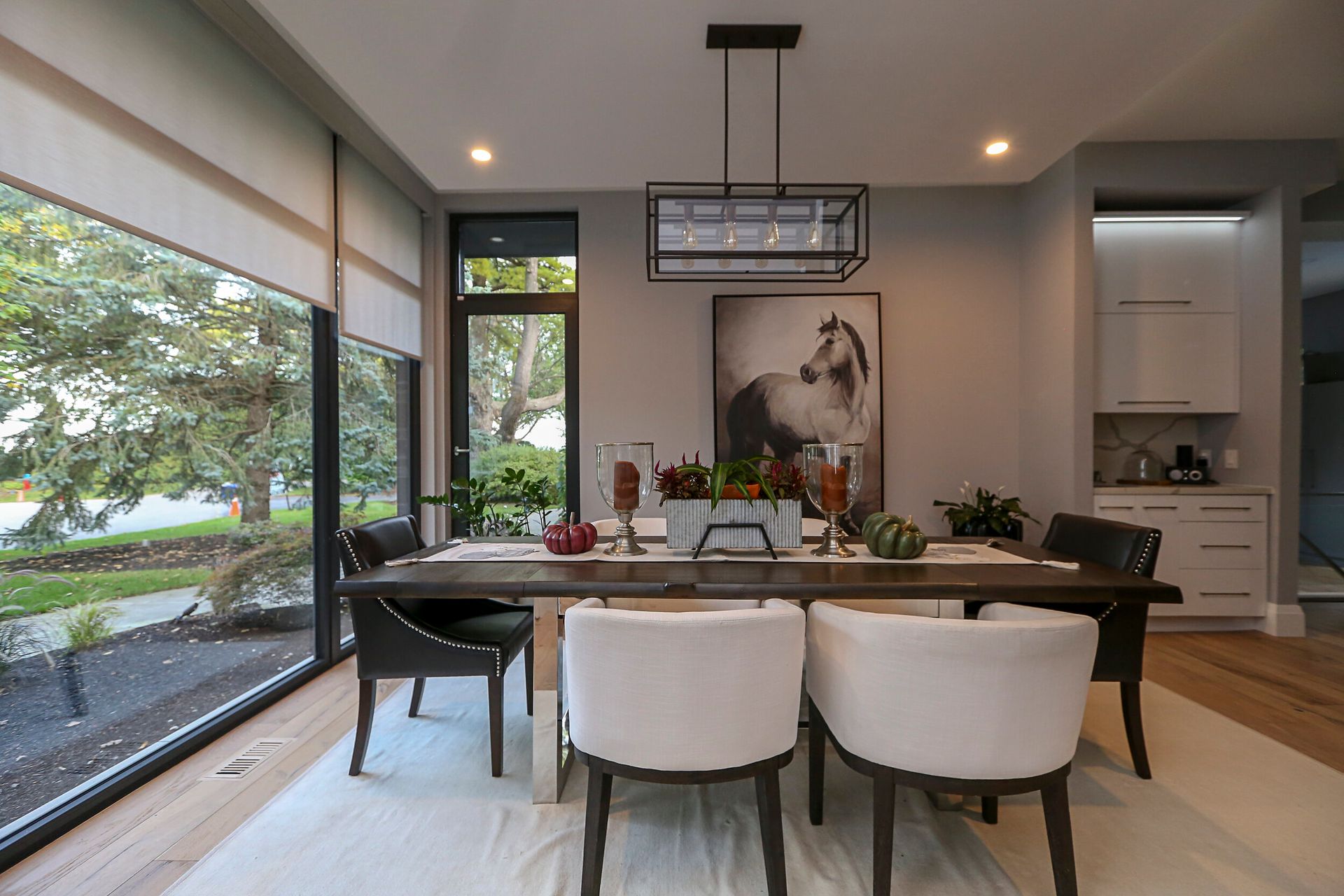 A dining room with a table and chairs and a horse painting on the wall