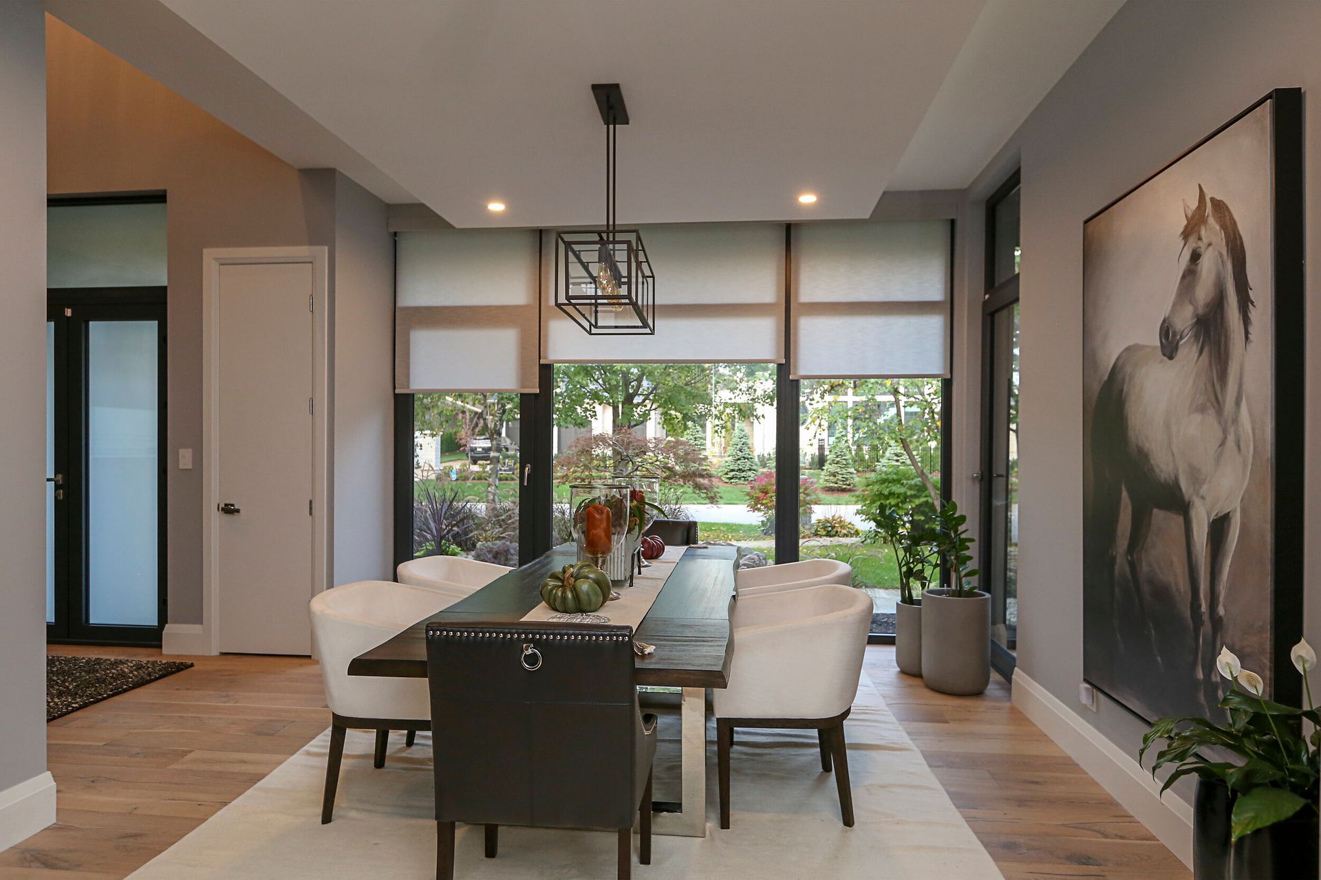 A dining room with a table and chairs and a painting of a horse on the wall