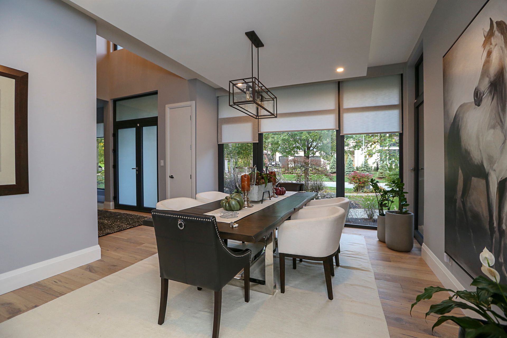 A dining room with a table and chairs and a painting of a horse on the wall.