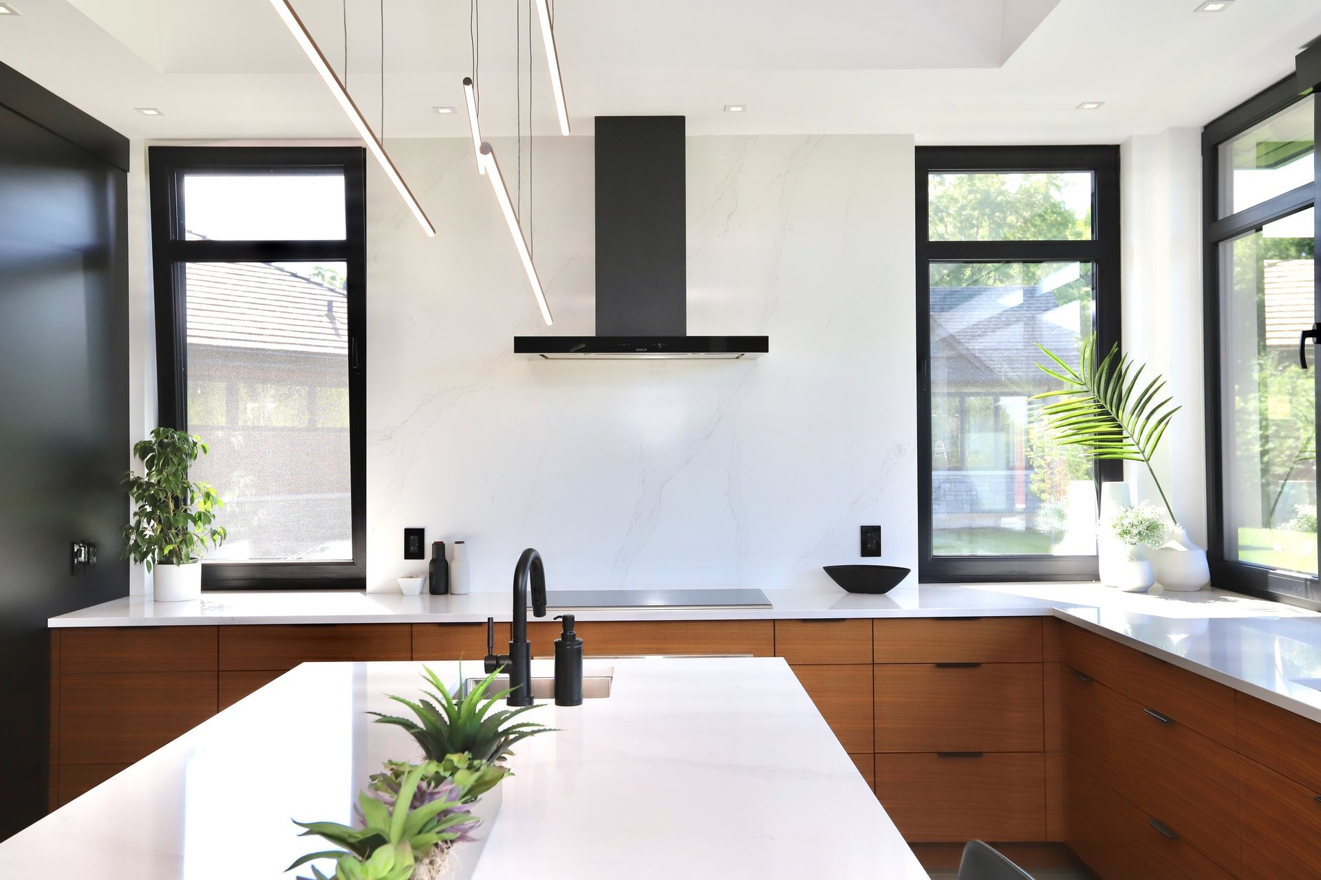 A kitchen with a large island , stove , sink , and windows.