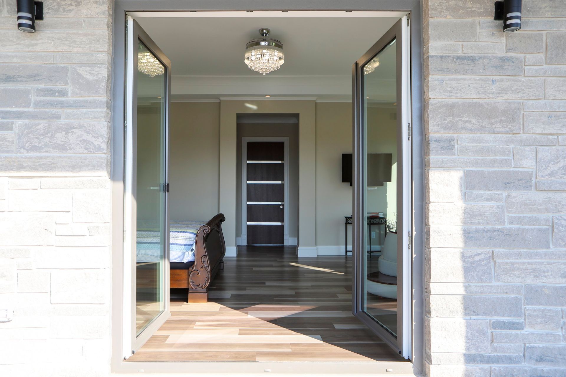 A large glass door is open to a hallway in a house.