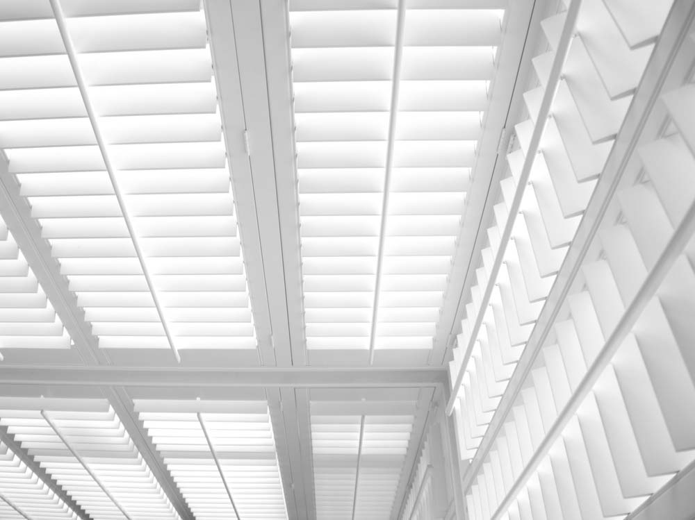 A black and white photo of a ceiling with white shutters.