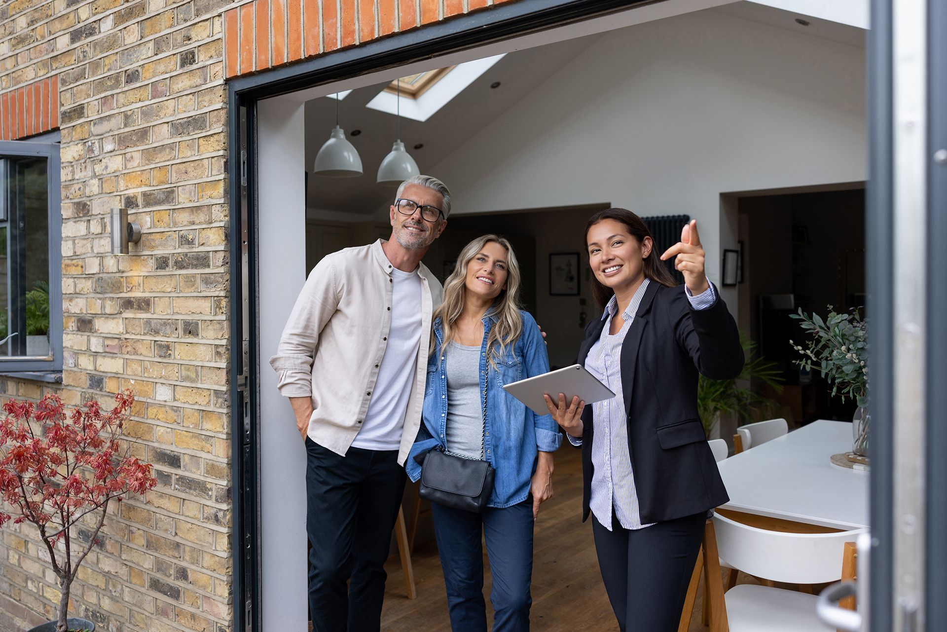 A man and woman are standing in front of a house with a real estate agent.