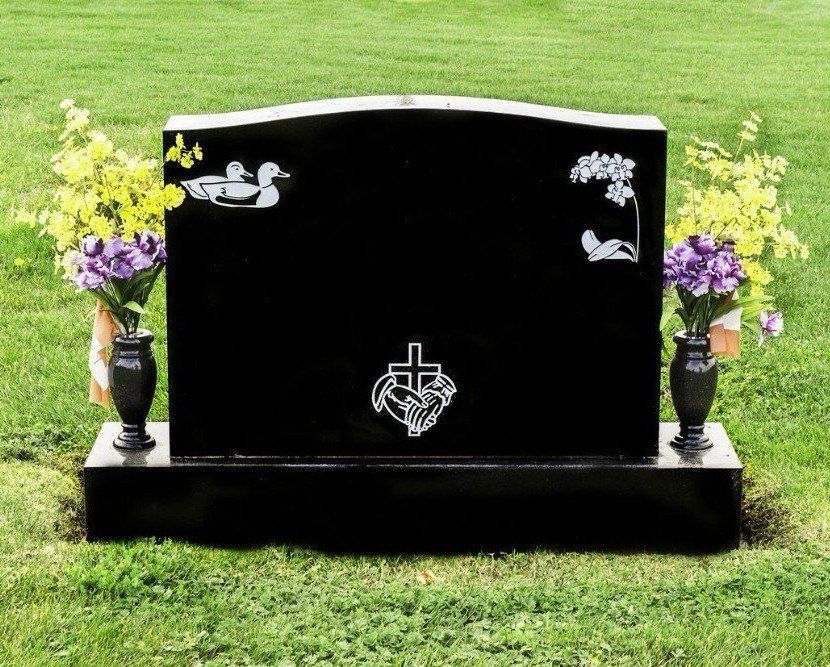 A black gravestone with two vases of flowers in front of it.