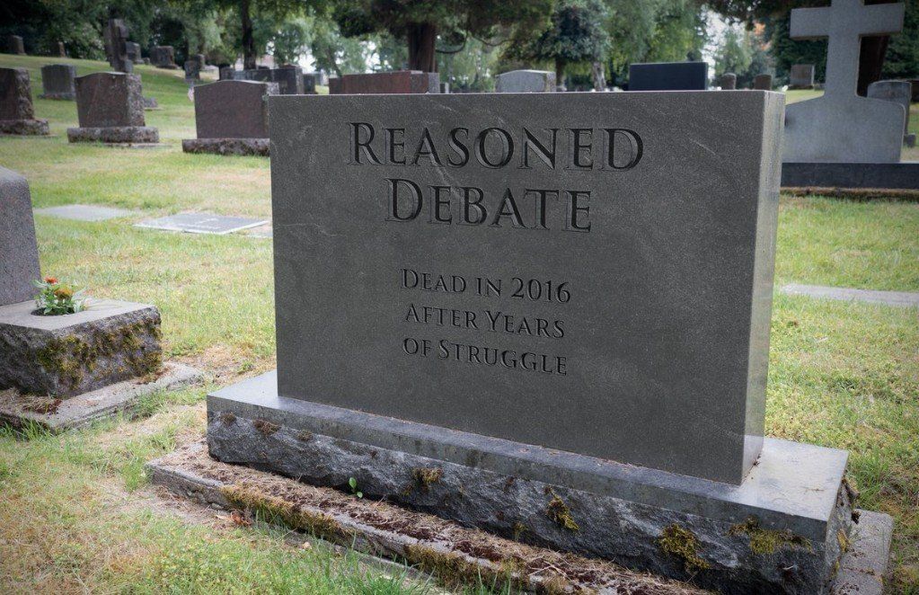 A gravestone that says reasoned debate in a cemetery