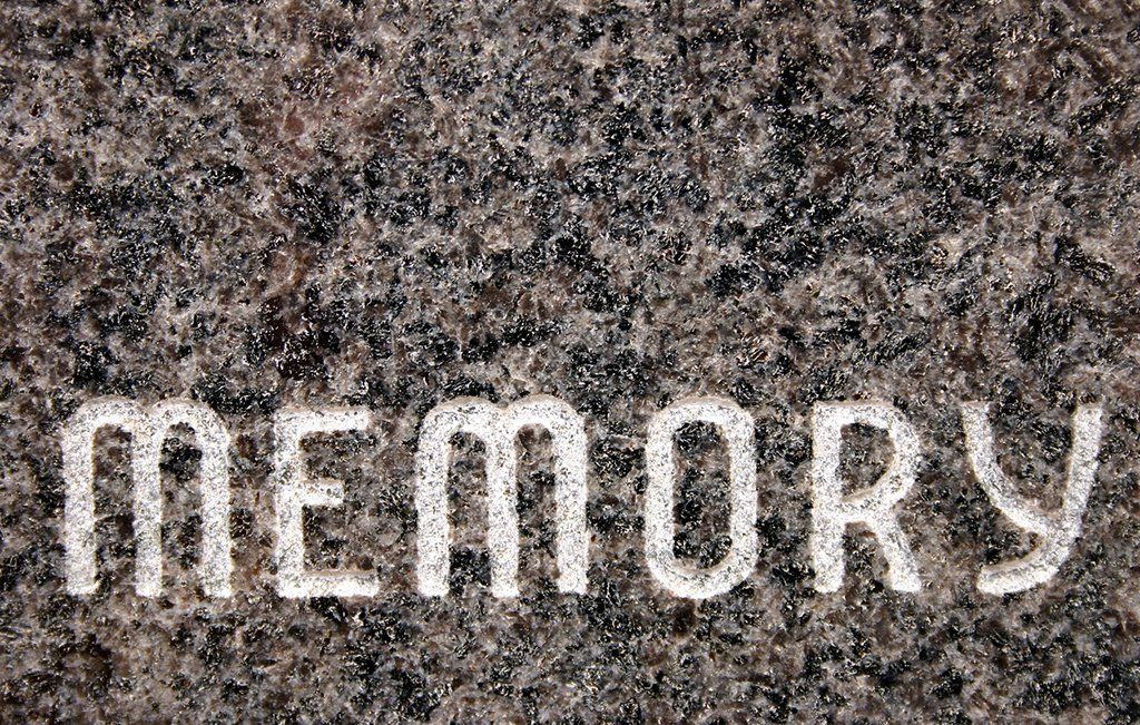 The word memory is carved into a stone surface.
