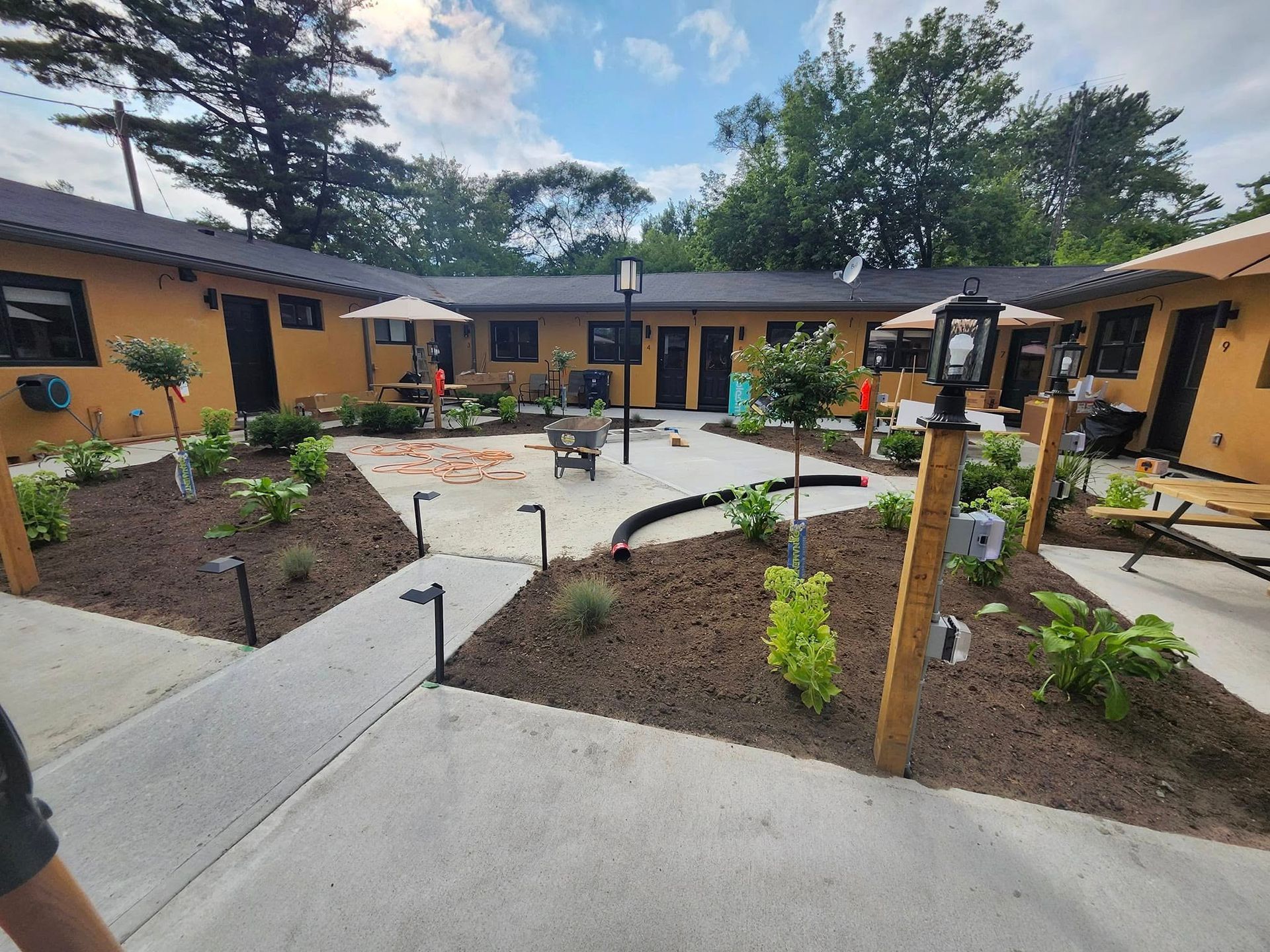 A courtyard at an inn or motel with tan walls, brown roofs, landscaping beds with mulch, and a concrete central walkway.