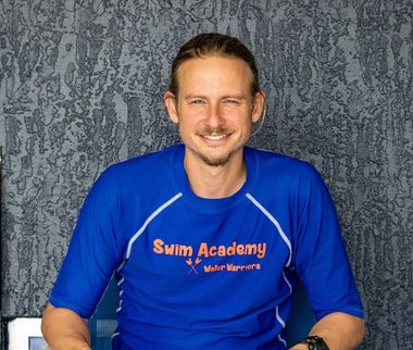 A man is wearing a blue swim academy shirt
