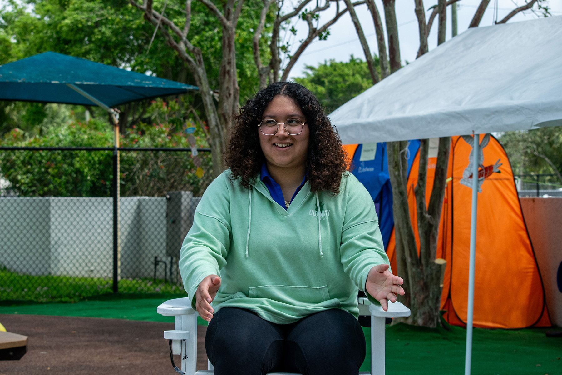 A woman is sitting on a picnic table under an umbrella.