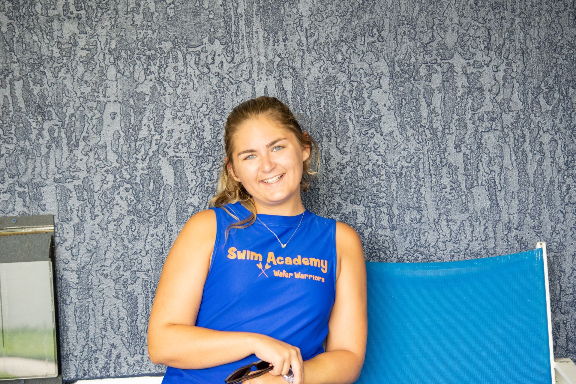 A woman wearing a blue tank top that says swim academy