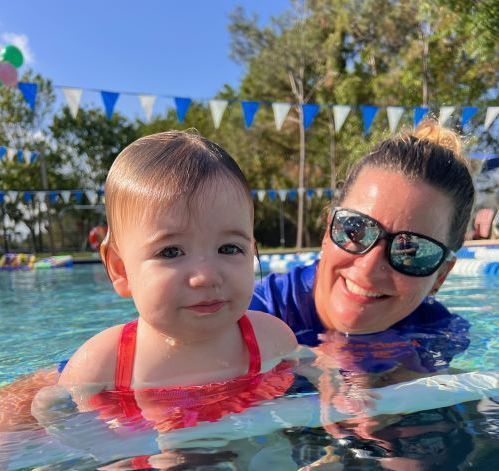 A woman is holding a baby in a swimming pool.