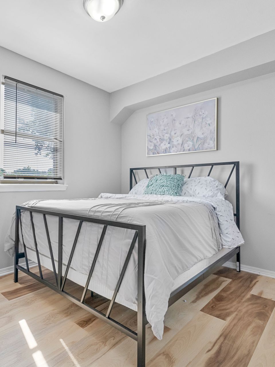 A bedroom with a bed and a window with blinds