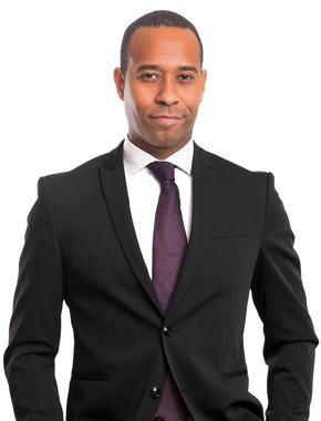 Man in black suit and purple tie, smiling slightly, looking at the camera. White background.