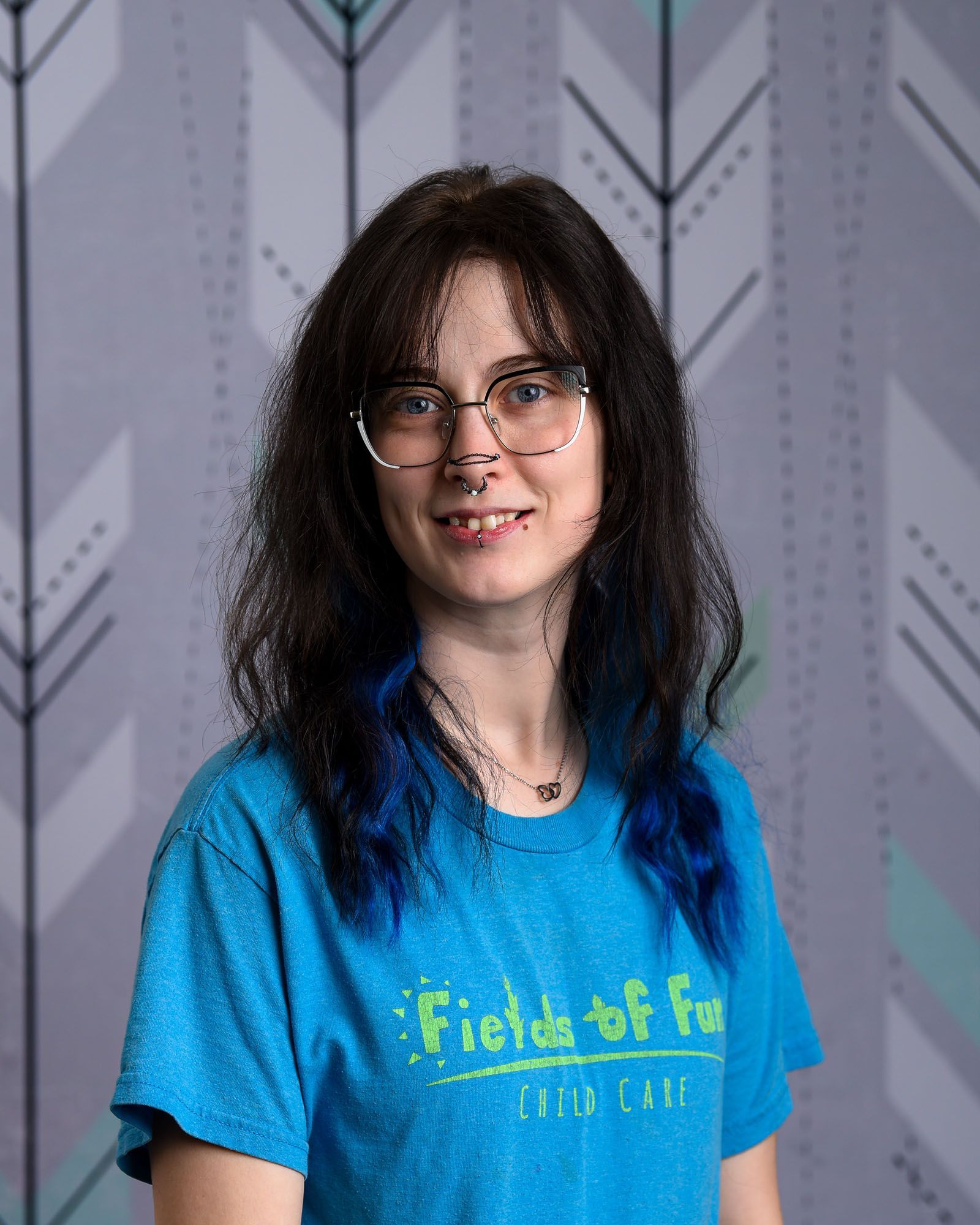 A woman with red hair is wearing a t-shirt that says fields of fun.