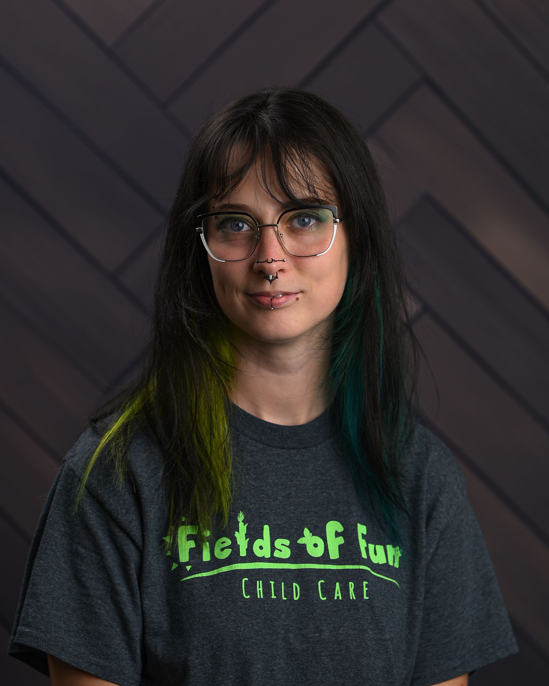 A woman with red hair is wearing a t-shirt that says fields of fun.