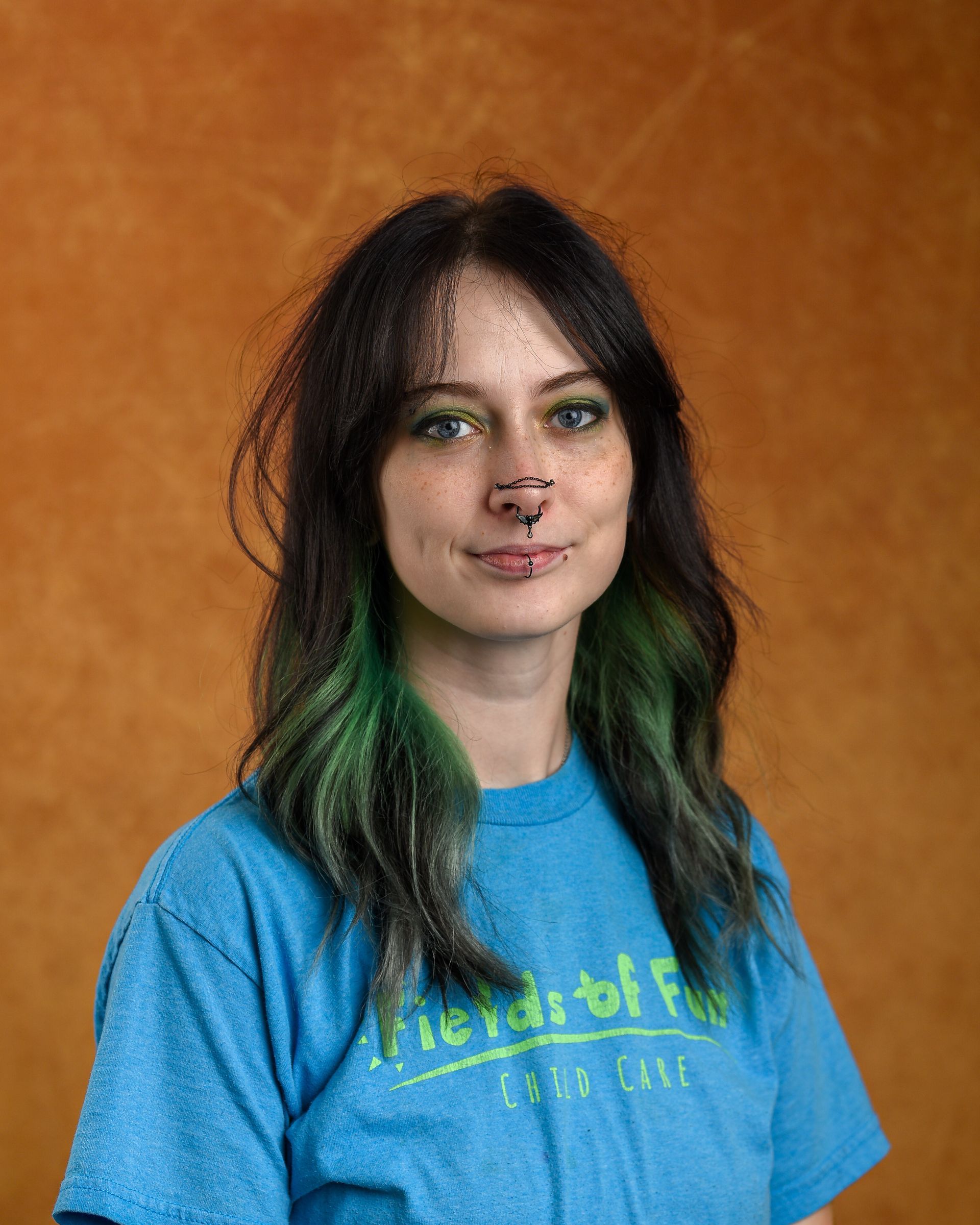 A woman with red hair is wearing a t-shirt that says fields of fun.