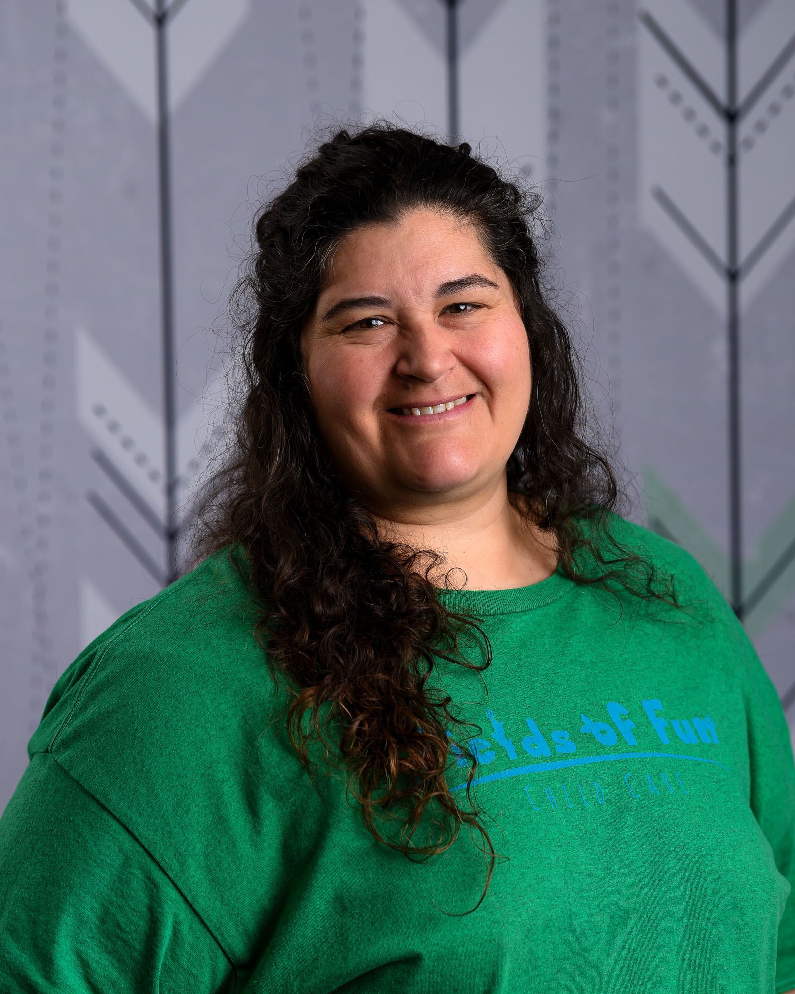 A woman wearing a fields of fun shirt is smiling for the camera.