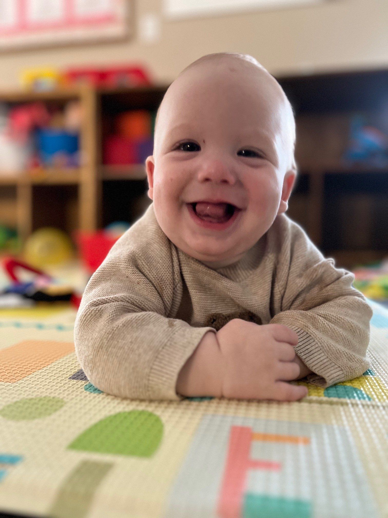 A baby is laying on a play mat and smiling.