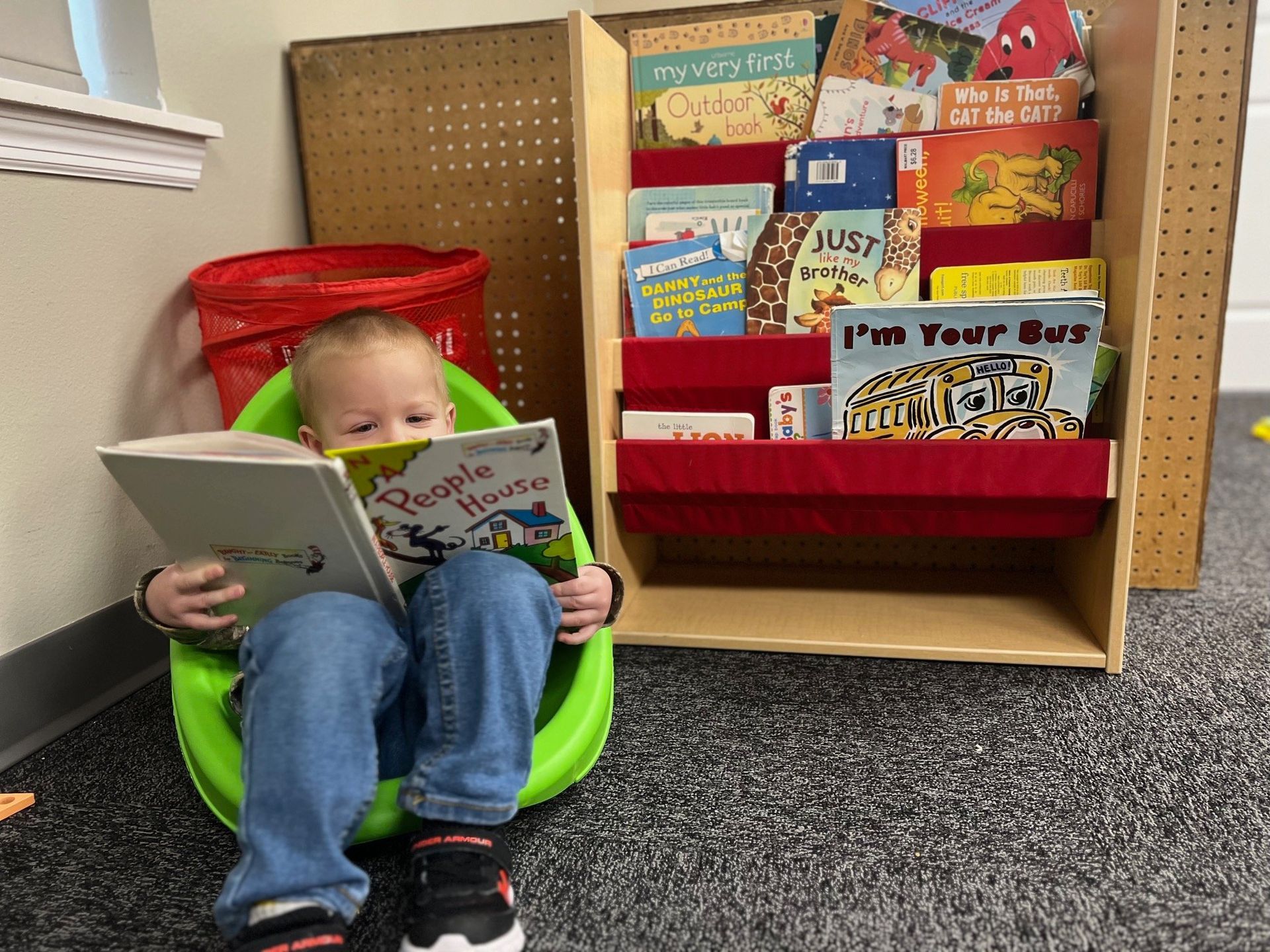 A young boy is sitting in a green chair reading a book