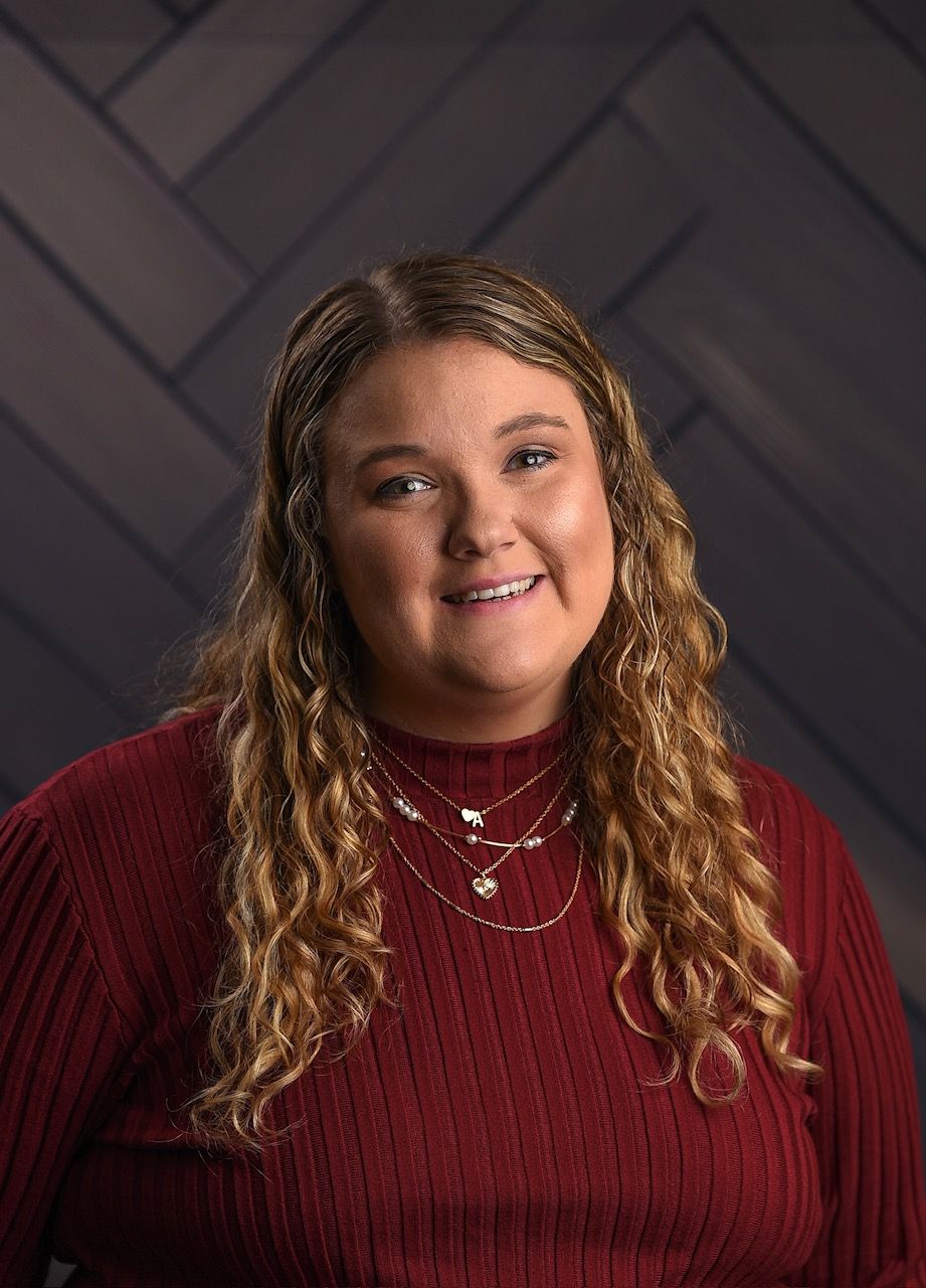 A woman wearing a plaid jacket and a black shirt is smiling for the camera.
