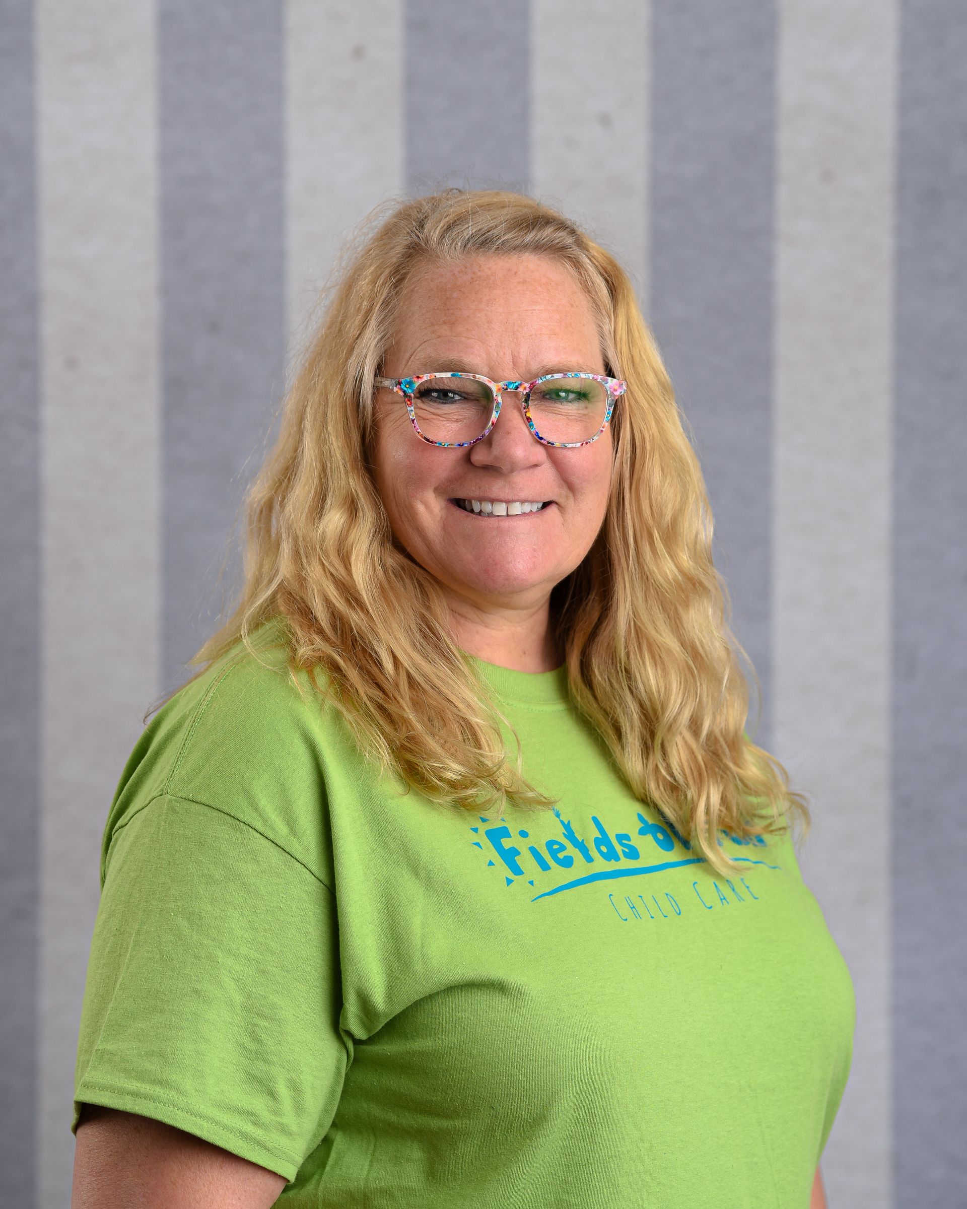 A woman wearing a plaid jacket and a black shirt is smiling for the camera.