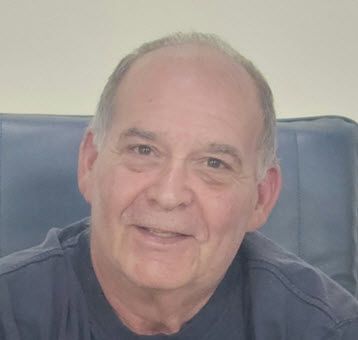 A man is sitting in a chair and smiling for the camera.