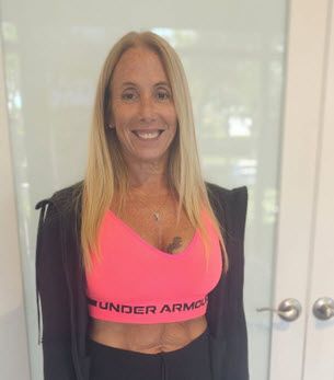 A woman is wearing a pink under armour sports bra and a black jacket.
