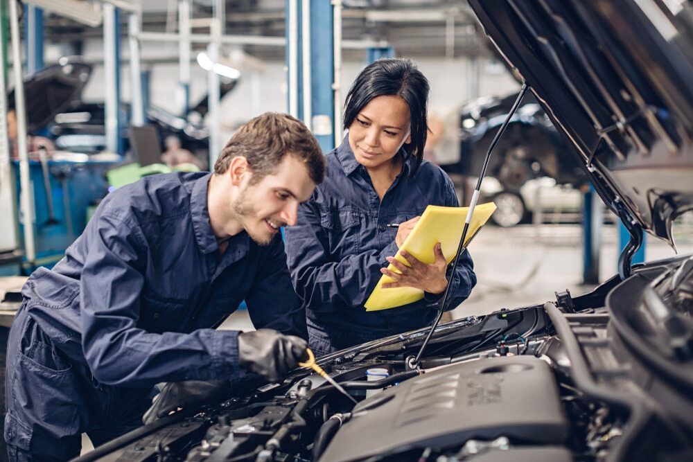 A Man And A Woman Are Working On A Car In A Garage — Mackay Car & Commercial Pty Ltd In Paget, QLD
