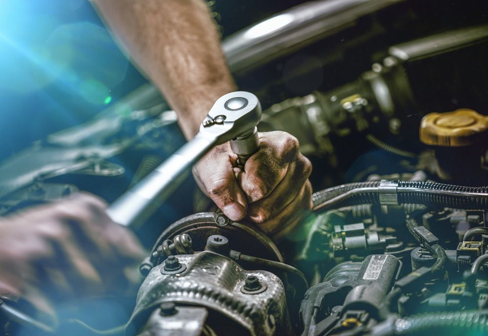 A Man Is Working On A Car Engine With A Wrench — Mackay Car & Commercial Pty Ltd In Paget, QLD