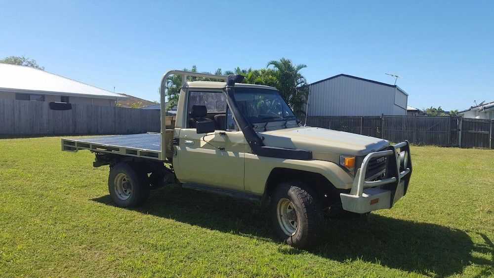 A Truck With A Flat Bed Is Parked In A Grassy Field — Mackay Car & Commercial Pty Ltd In Paget, QLD