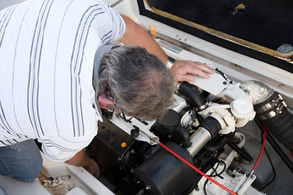 A Man Is Working On The Engine Of A Boat — Mackay Car & Commercial Pty Ltd In Paget, QLD