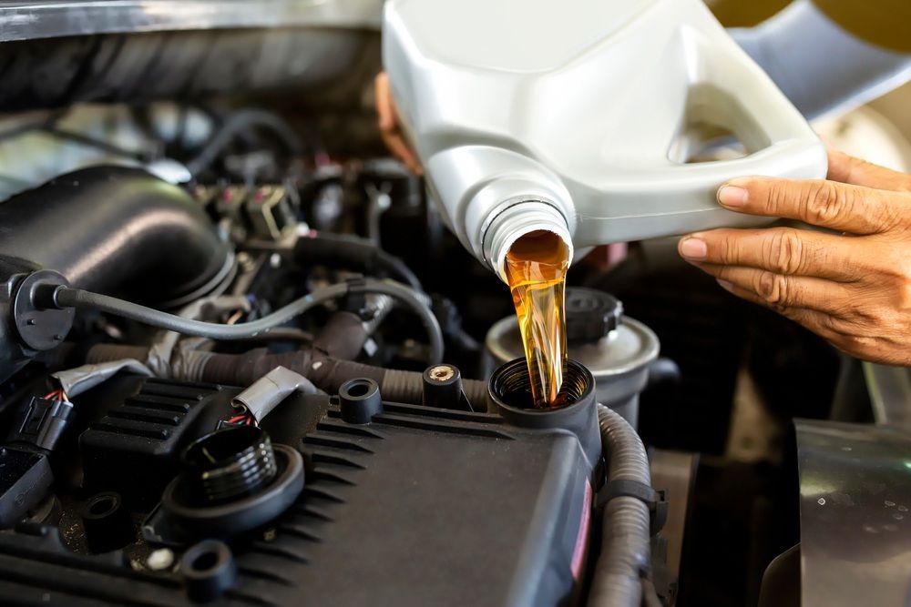A Person Is Pouring Oil Into A Car Engine — Mackay Car & Commercial Pty Ltd In Paget, QLD