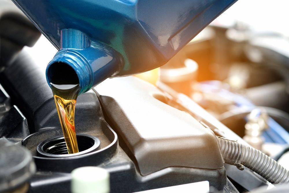 A Person Is Pouring Oil Into A Car Engine — Mackay Car & Commercial Pty Ltd In Paget, QLD