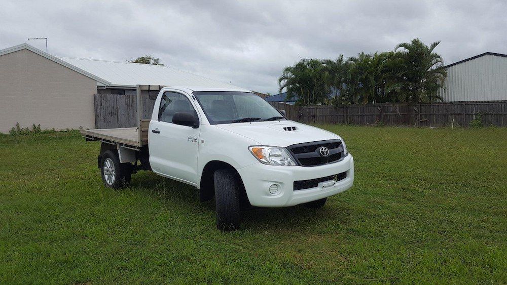 A White Truck With A Flat Bed Is Parked In A Grassy Field — Mackay Car & Commercial Pty Ltd In Paget, QLD