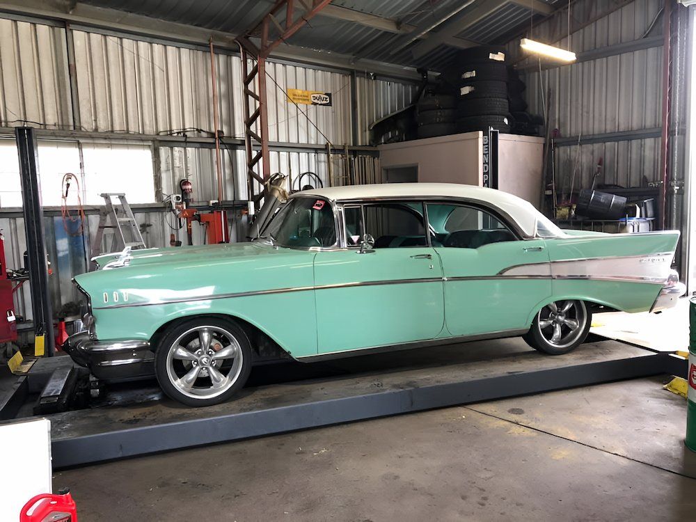 A Green And White Classic Car Is Parked On A Lift In A Garage — Mackay Car & Commercial Pty Ltd In Paget, QLD