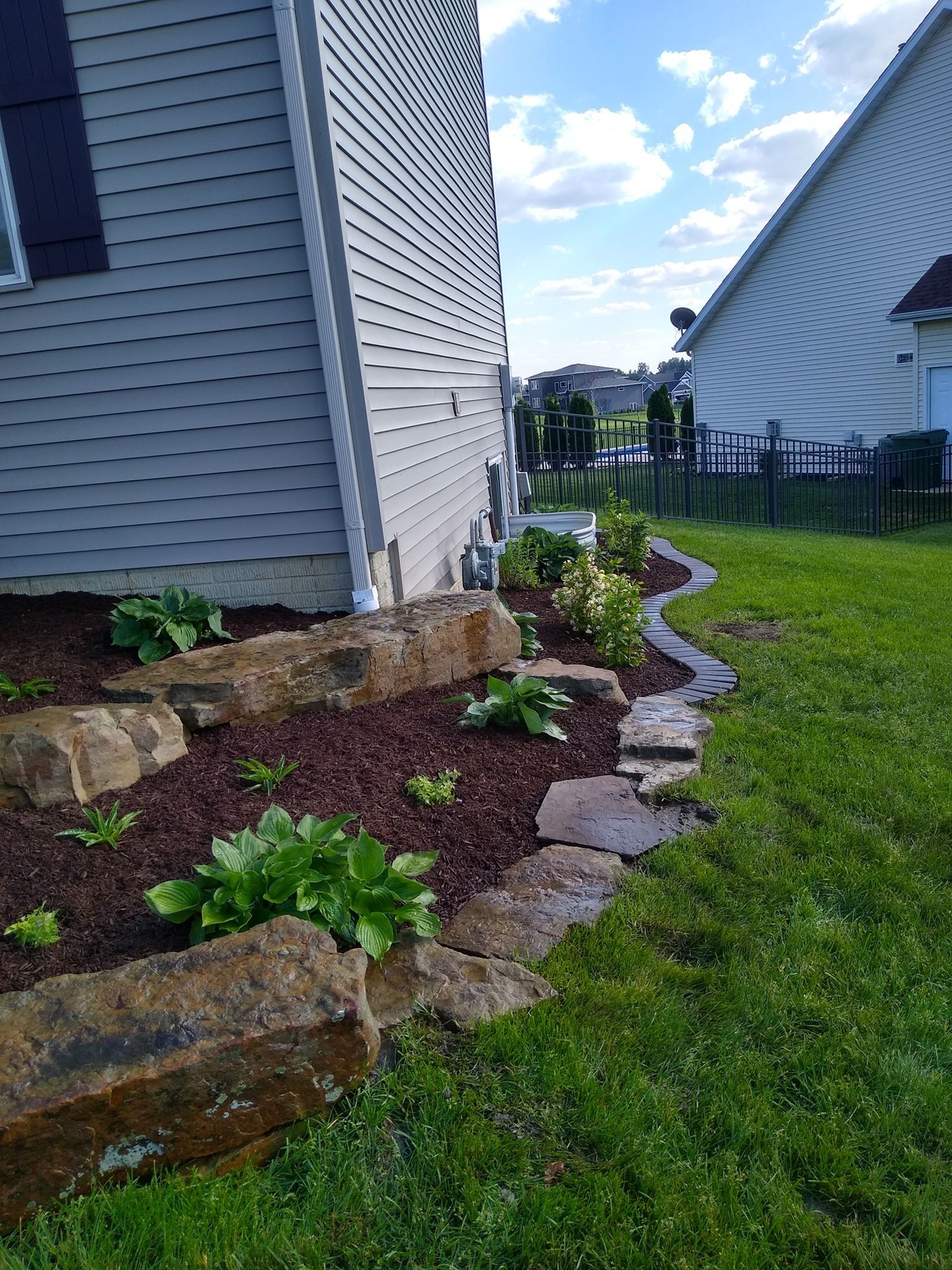 A house with a lawn and rocks in front of it.
