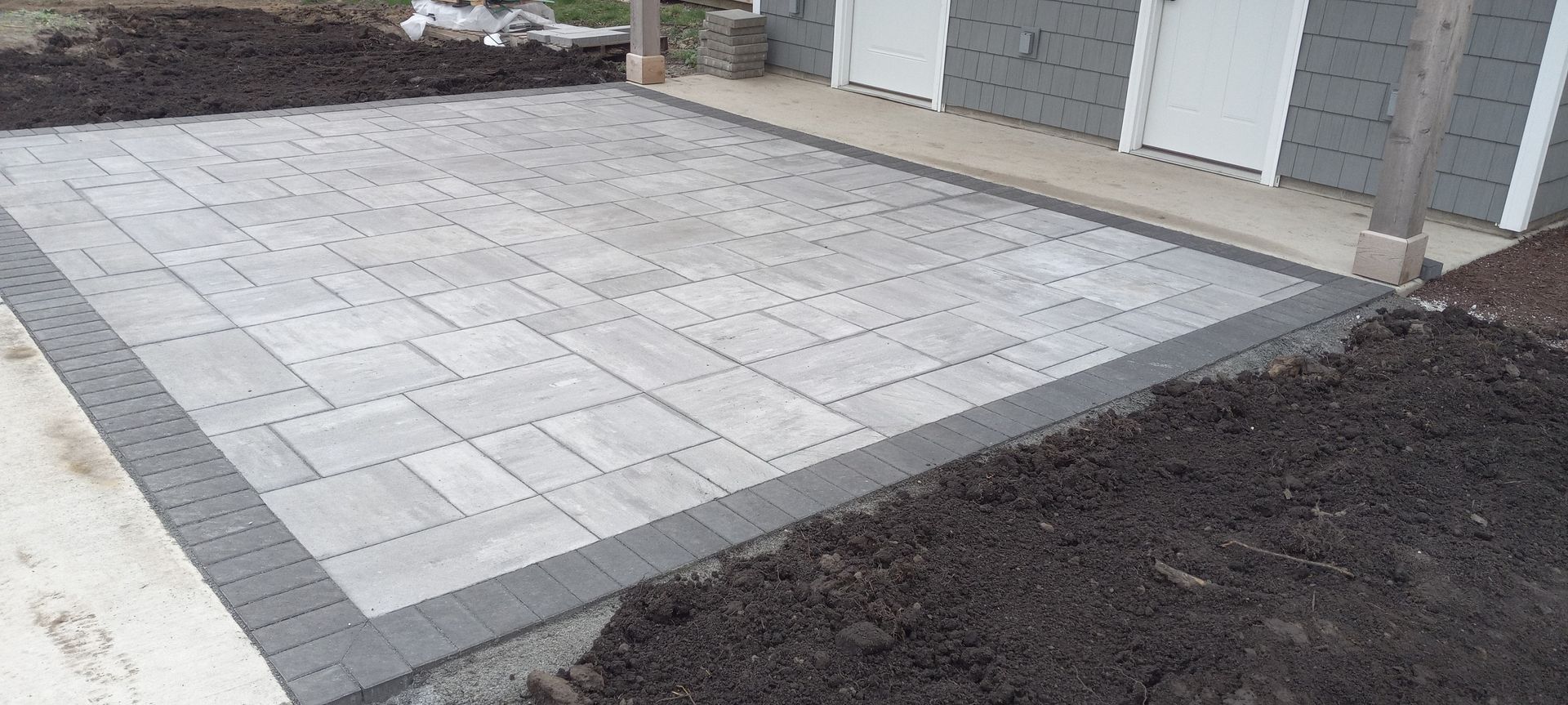 A brick driveway is being built in front of a house.
