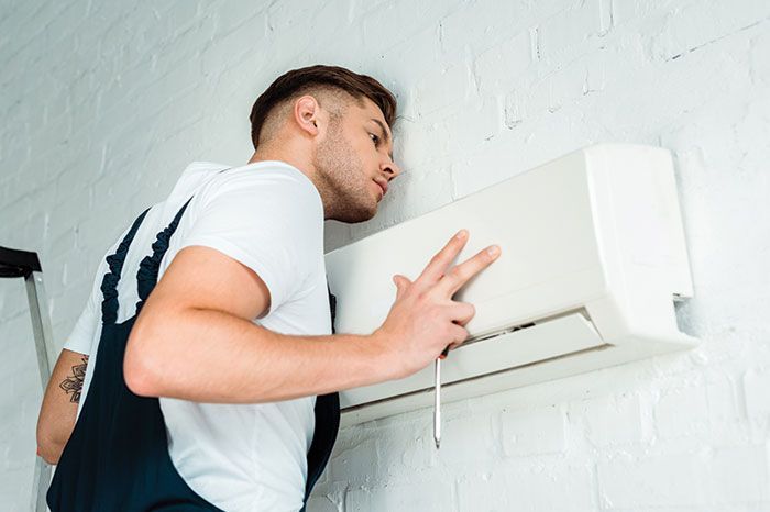 a man is installing an air conditioner on a wall .