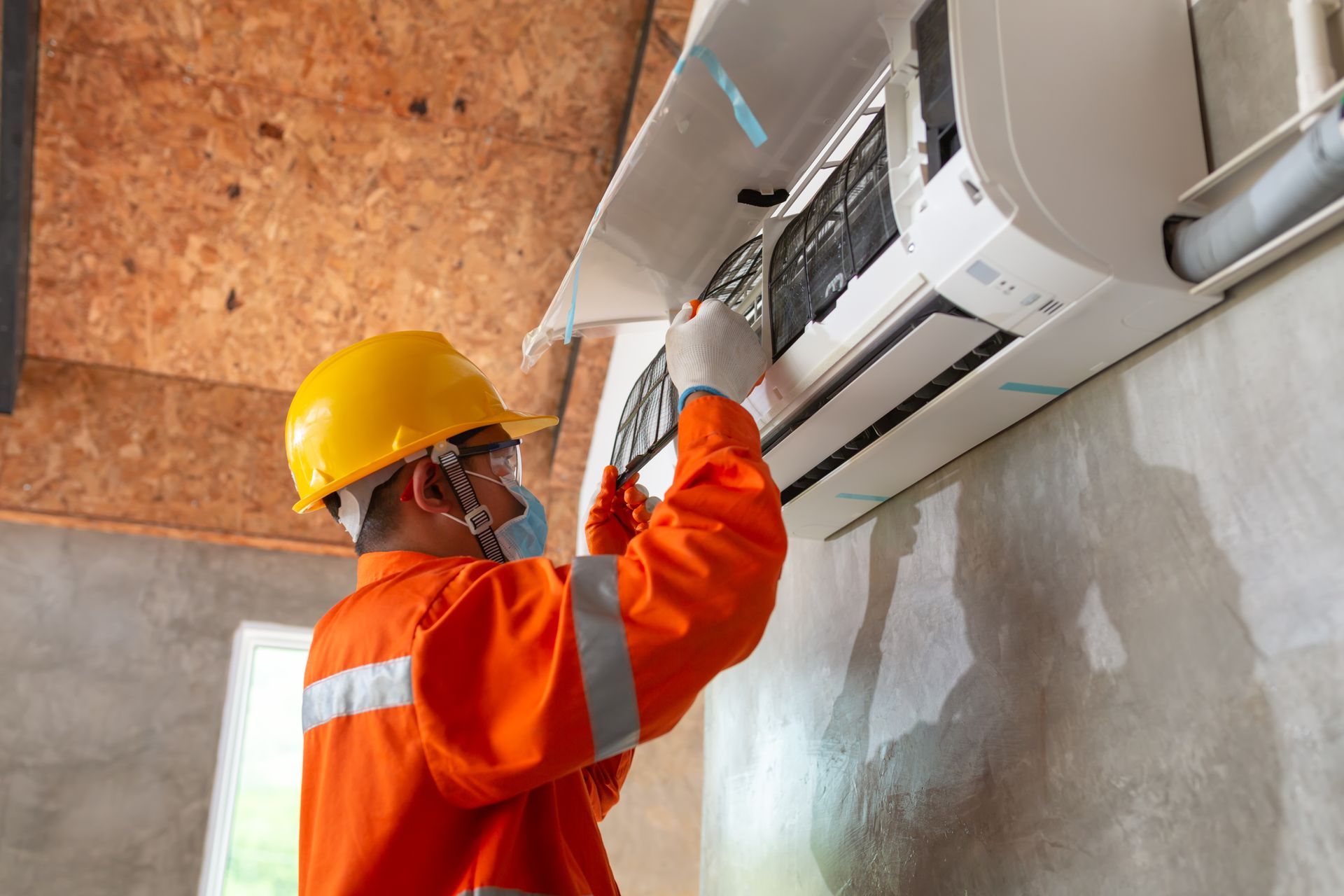 a man is fixing an air conditioner on a wall .