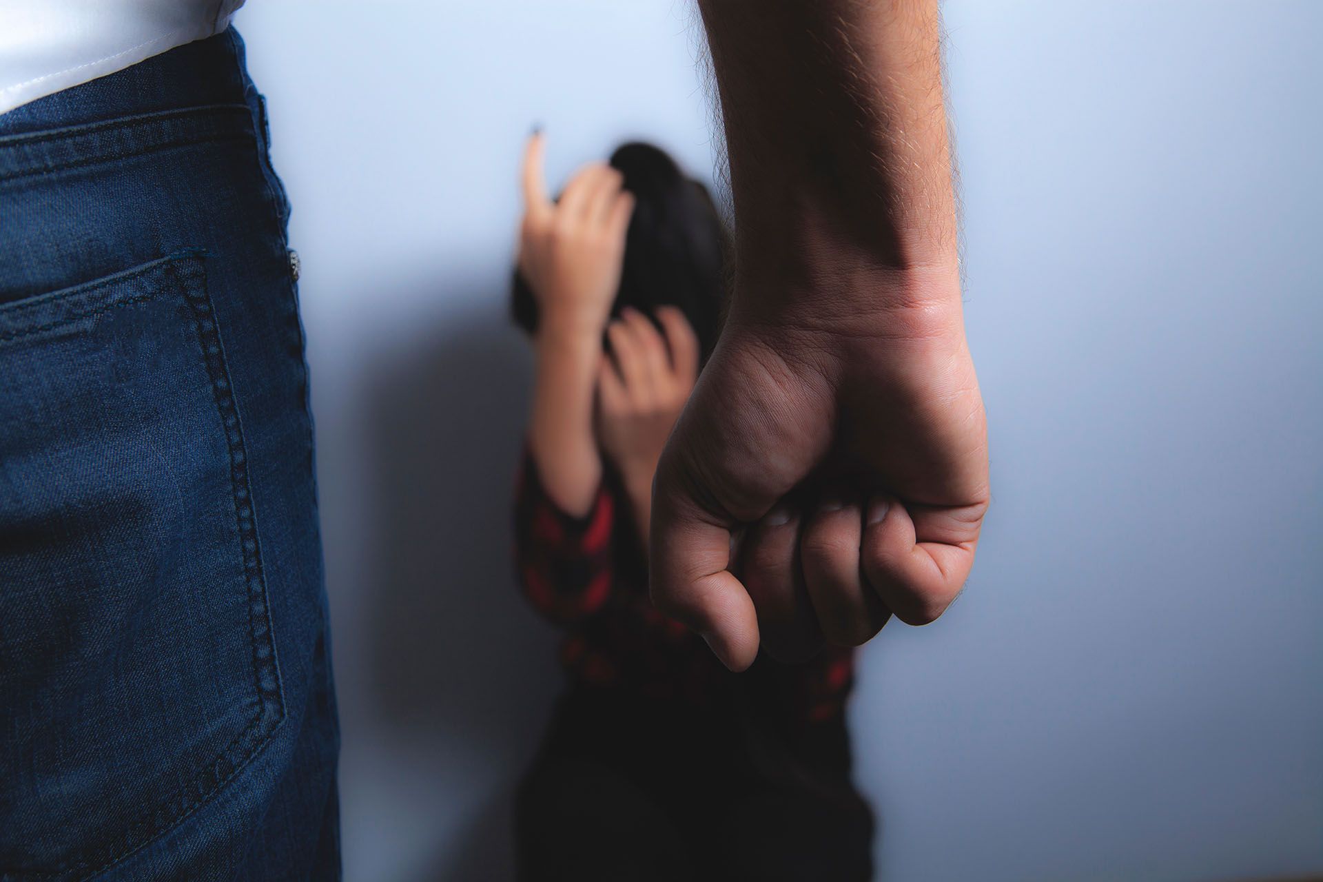 A man is holding a child 's hand in front of a wall.