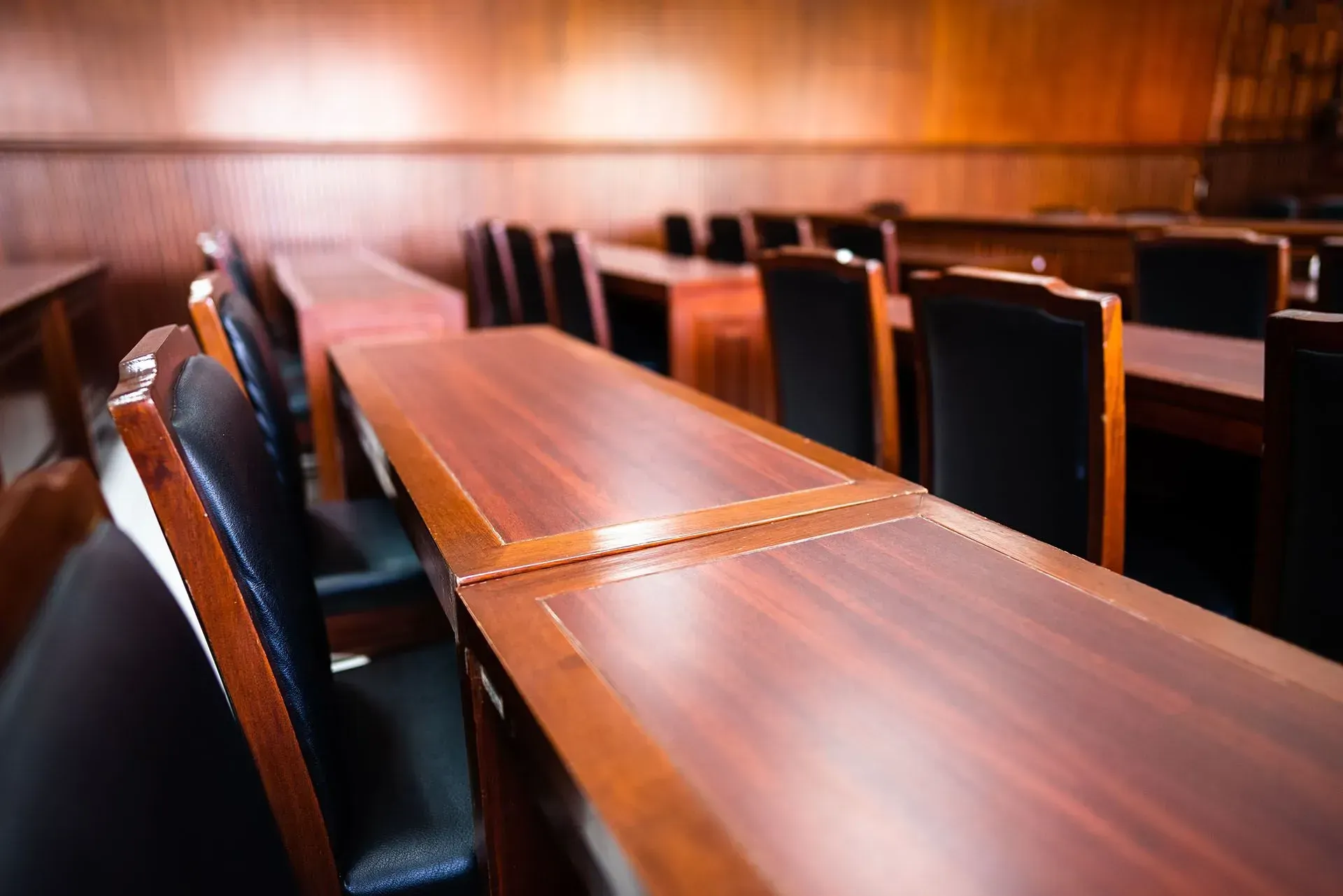 rows of wooden tables and chairs in a courtroom