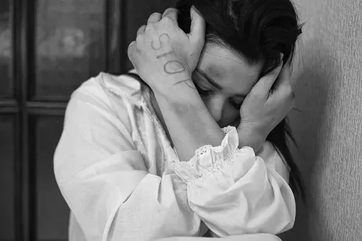 A black and white photo of a woman with her hands written on her face.