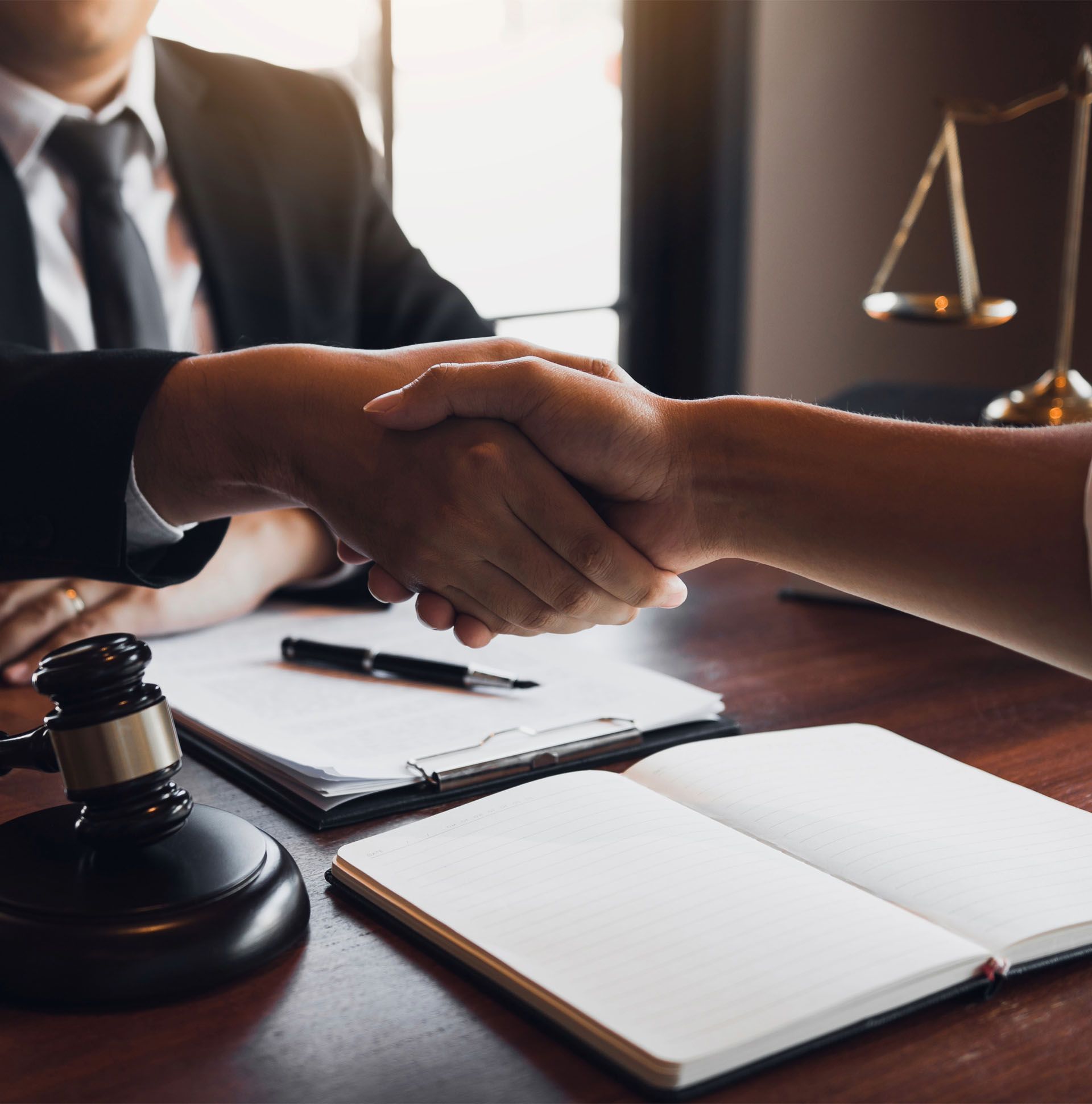 A man and a woman are shaking hands in front of a judge 's gavel.