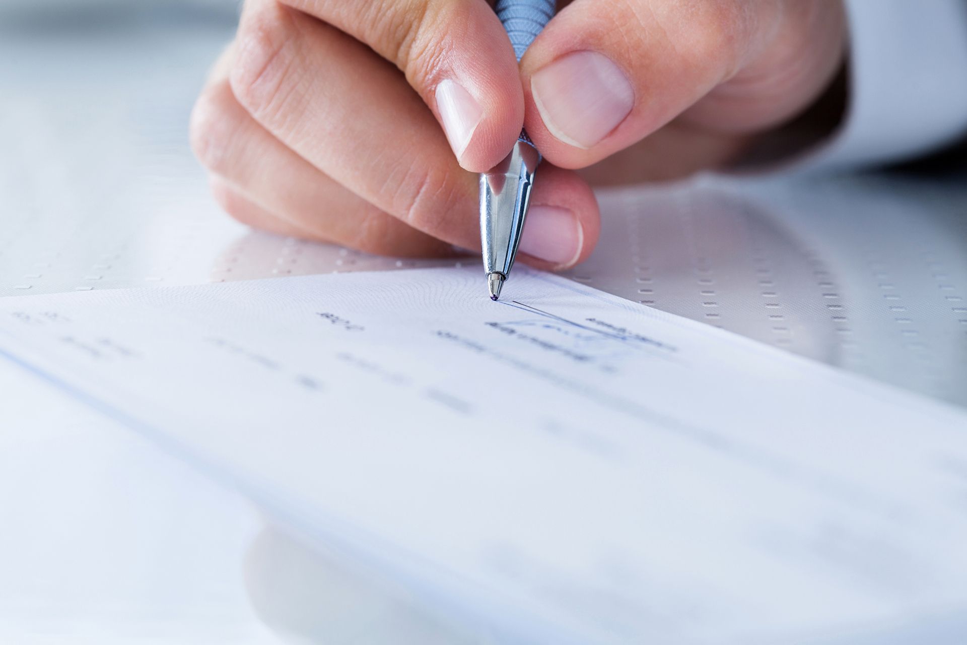 A person is writing on a piece of paper with a pen.